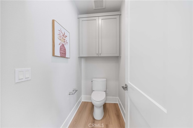 bathroom with toilet, wood finished floors, visible vents, and baseboards