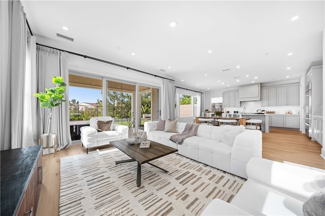 living room with light wood-style flooring, visible vents, and recessed lighting