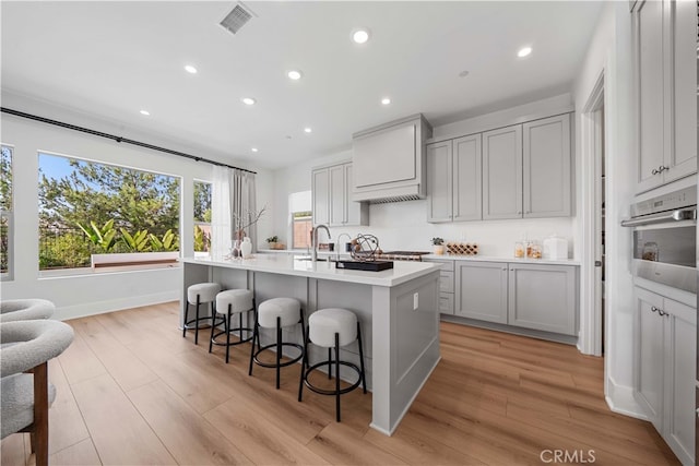 kitchen featuring an island with sink, light wood-style floors, appliances with stainless steel finishes, and light countertops