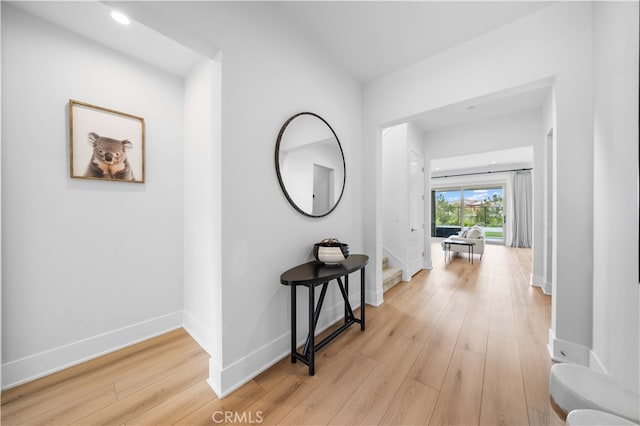 corridor with recessed lighting, baseboards, light wood finished floors, and stairs