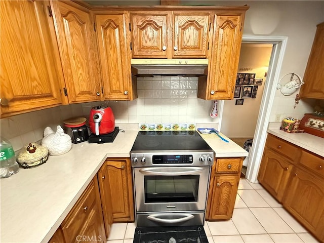 kitchen with electric stove, tasteful backsplash, and light tile patterned flooring