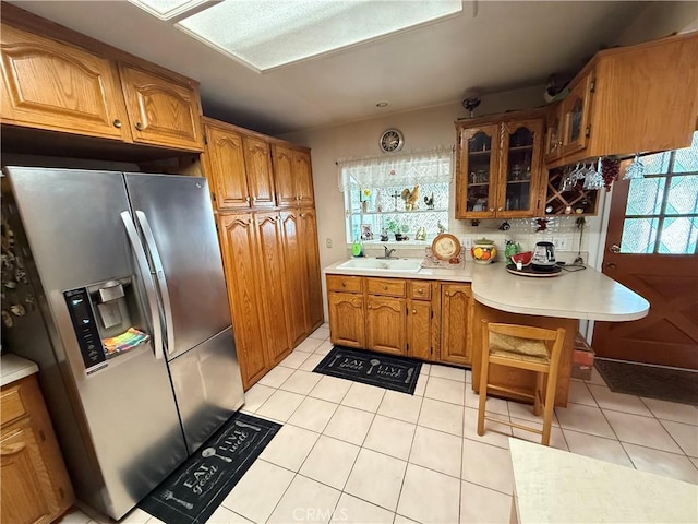 kitchen with stainless steel refrigerator with ice dispenser, sink, and light tile patterned floors