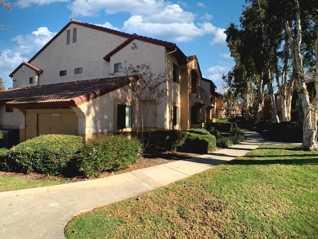 view of side of home with a balcony and a yard