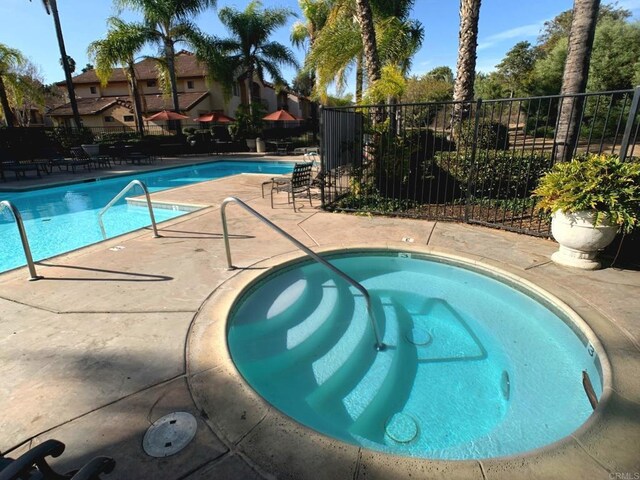 view of swimming pool featuring a community hot tub and a patio area