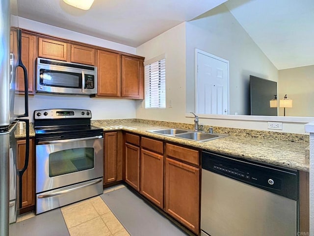 kitchen featuring sink, vaulted ceiling, light tile patterned floors, kitchen peninsula, and stainless steel appliances