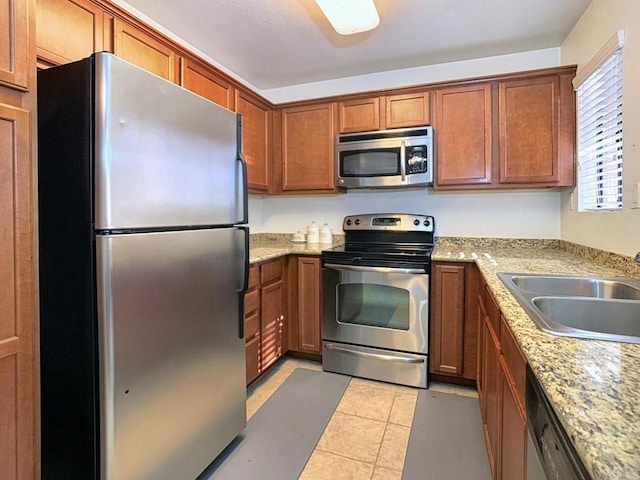 kitchen with light stone countertops, appliances with stainless steel finishes, sink, and light tile patterned floors