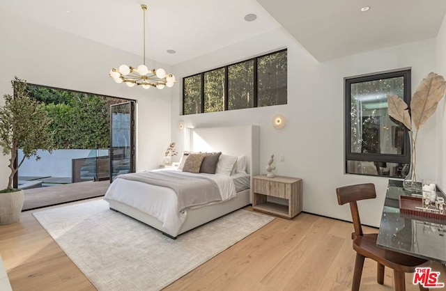 bedroom with access to outside, a notable chandelier, and light wood-type flooring