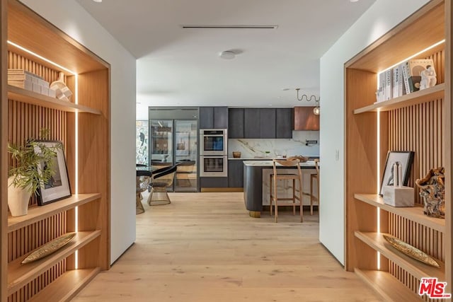 kitchen featuring appliances with stainless steel finishes, backsplash, and light wood-type flooring