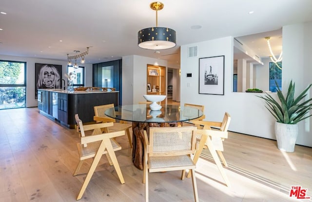 dining area with track lighting, a chandelier, and light wood-type flooring