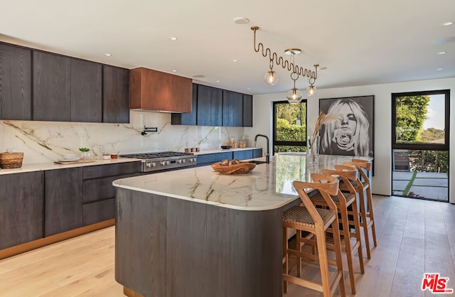 kitchen with hanging light fixtures, an island with sink, a healthy amount of sunlight, and stainless steel gas cooktop