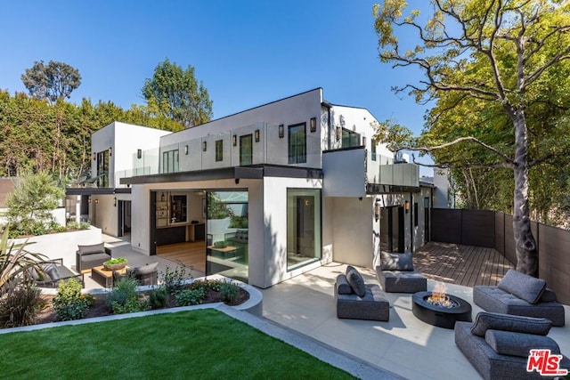 rear view of property featuring a patio and an outdoor living space with a fire pit