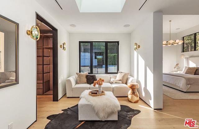 living room featuring a skylight, light hardwood / wood-style floors, and a chandelier