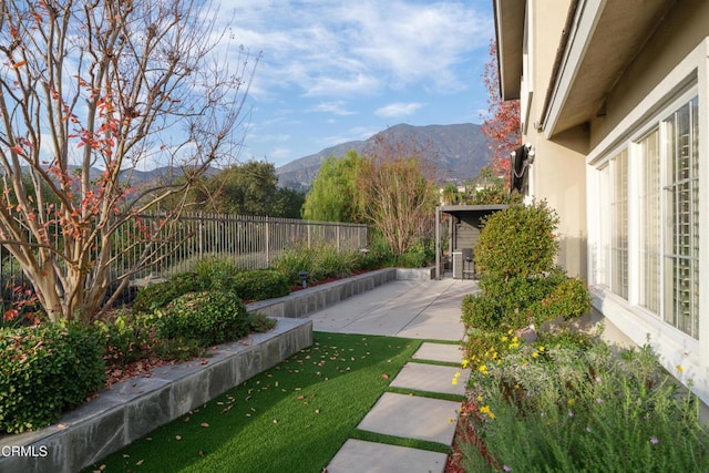 view of yard featuring a patio, fence, and a mountain view