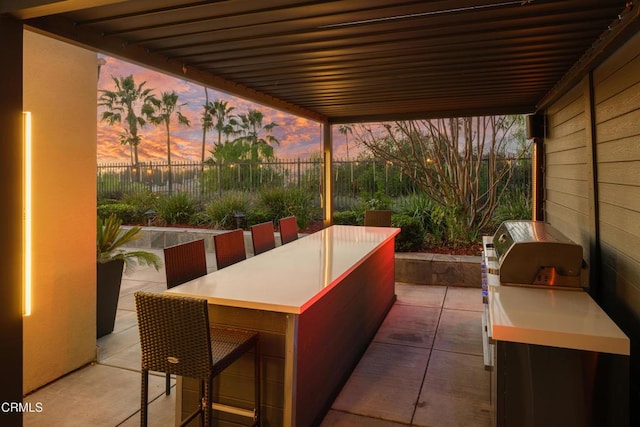 view of patio featuring outdoor dining space, fence, and an outdoor kitchen