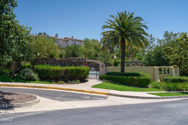 exterior space with a gate, curbs, and sidewalks