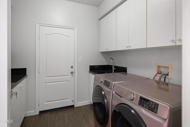 clothes washing area with cabinet space, baseboards, dark wood-type flooring, independent washer and dryer, and a sink