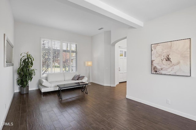 living room featuring arched walkways, visible vents, baseboards, and wood finished floors