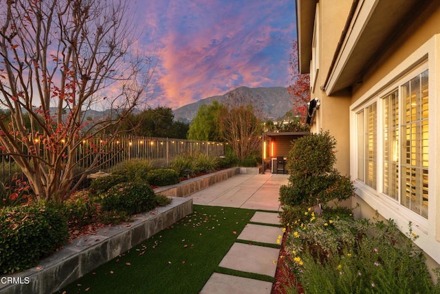 view of yard featuring a patio area, fence, and a mountain view