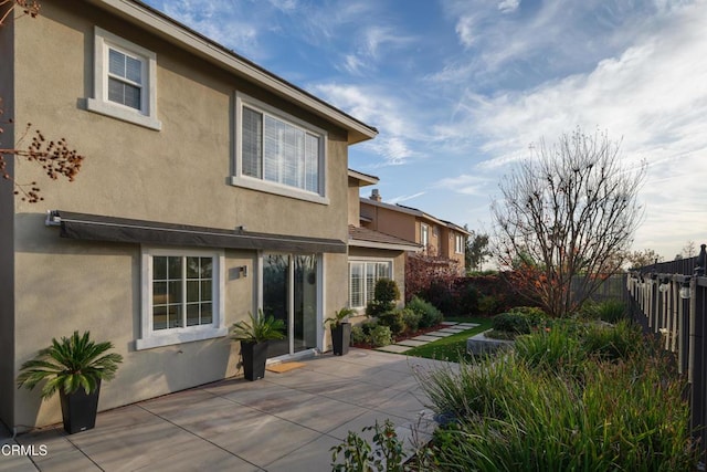 back of house featuring a patio, fence, and stucco siding