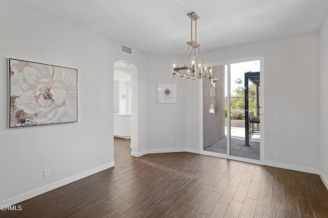 spare room featuring arched walkways, dark wood-style flooring, visible vents, and baseboards