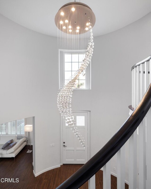 entryway with a chandelier, wood finished floors, a high ceiling, and stairs