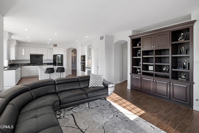 living room with arched walkways, wood finished floors, visible vents, and recessed lighting