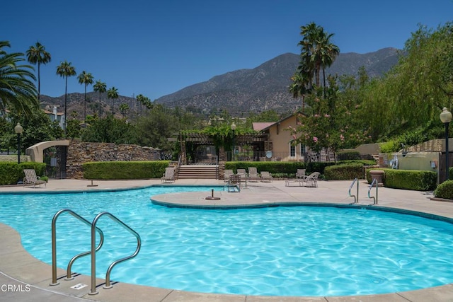 community pool with a patio area, fence, and a mountain view