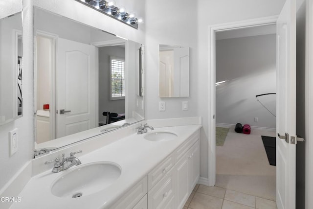 full bath featuring double vanity, tile patterned flooring, baseboards, and a sink