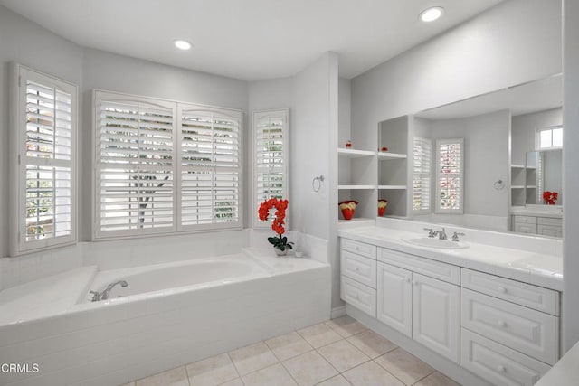 full bath with a wealth of natural light, tile patterned flooring, a garden tub, and vanity