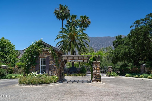 exterior space featuring stone siding, a gate, a mountain view, and fence