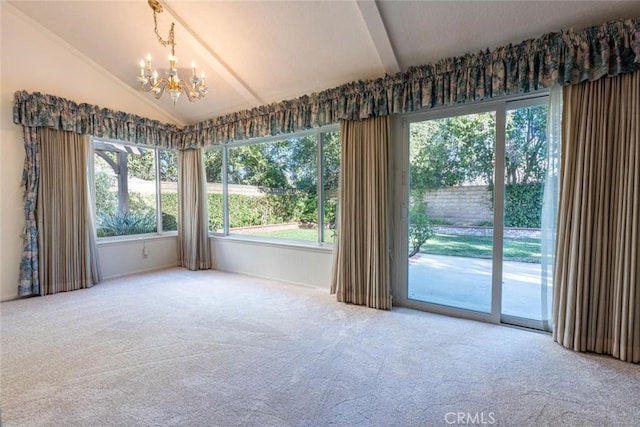 carpeted spare room featuring plenty of natural light, lofted ceiling, and an inviting chandelier