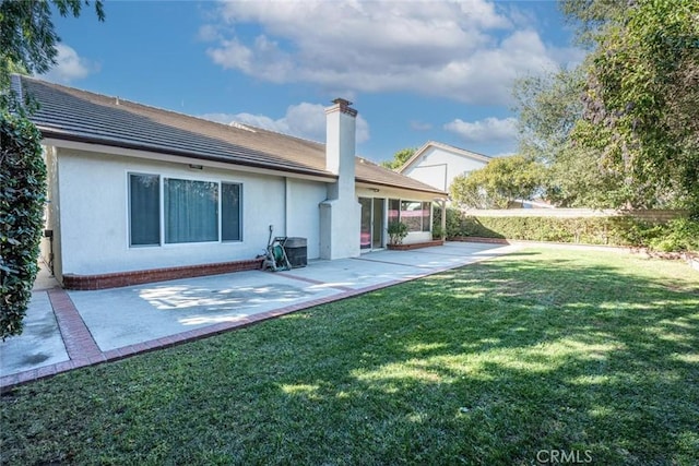 back of house featuring a lawn and a patio