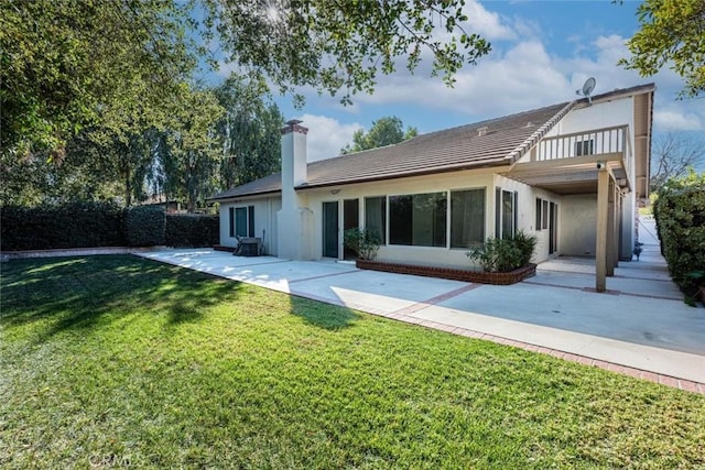 rear view of property featuring a patio area, a balcony, and a yard