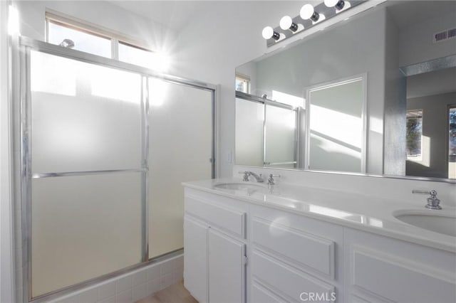 bathroom with a shower with shower door and vanity