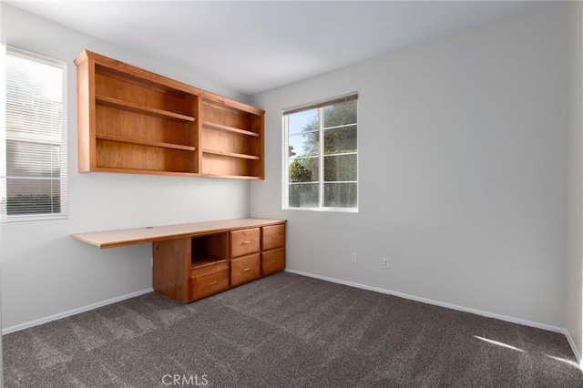 unfurnished office featuring a wealth of natural light and dark carpet