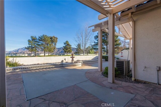 view of patio featuring central AC, a pergola, and a mountain view