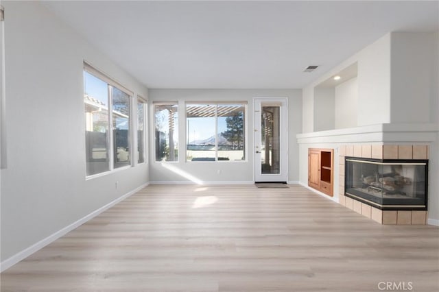 unfurnished living room with light hardwood / wood-style floors and a tiled fireplace