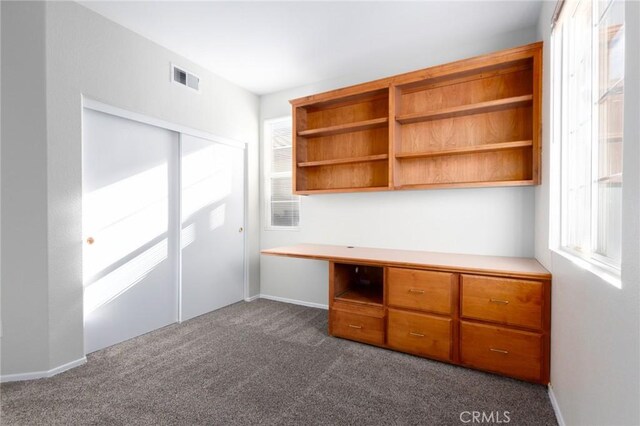 unfurnished office featuring a healthy amount of sunlight and dark colored carpet