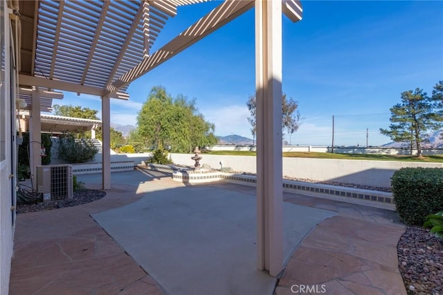 view of patio featuring a mountain view, central AC, and a pergola