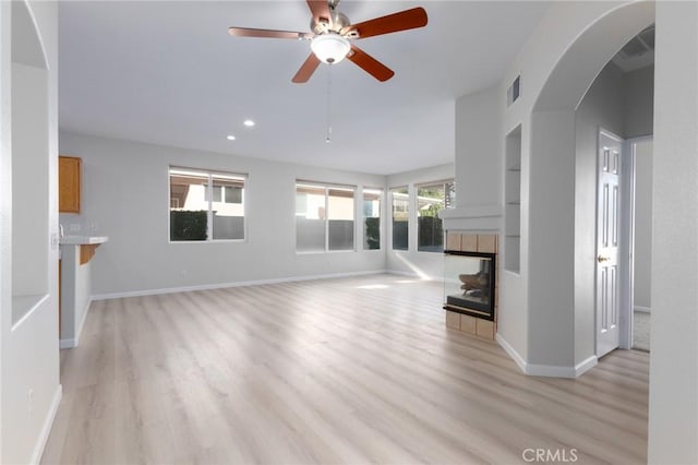 unfurnished living room featuring ceiling fan, a fireplace, and light hardwood / wood-style floors