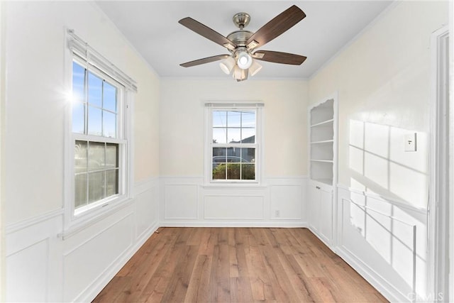 unfurnished room featuring ceiling fan, built in features, and light hardwood / wood-style floors