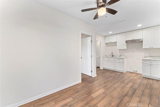 kitchen featuring ceiling fan, sink, and white cabinets