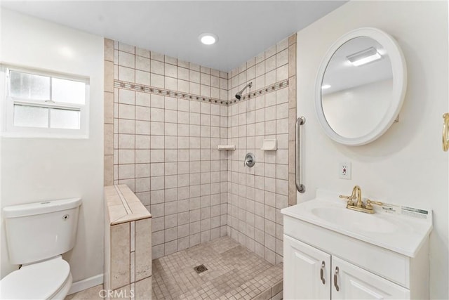 bathroom featuring toilet, tiled shower, and vanity