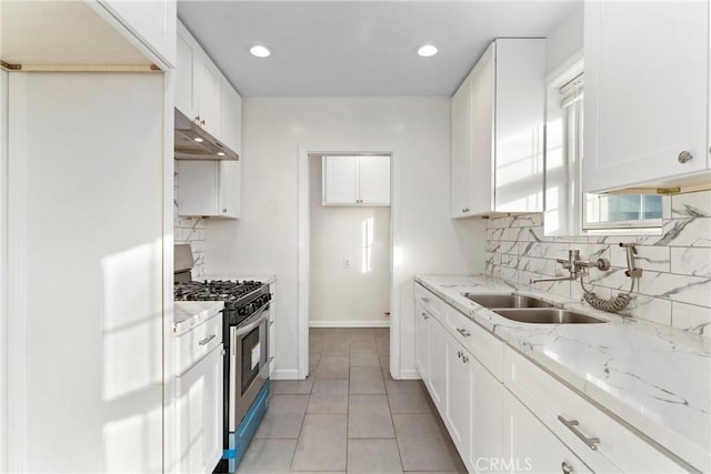 kitchen with light stone countertops, stainless steel range with gas cooktop, white cabinets, and sink