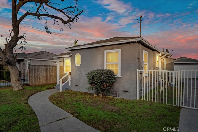 property exterior at dusk featuring a yard