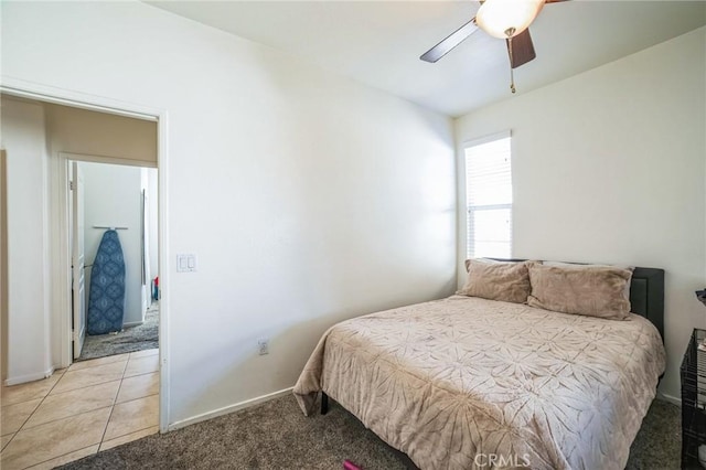 bedroom featuring light tile patterned floors, baseboards, a ceiling fan, and light colored carpet