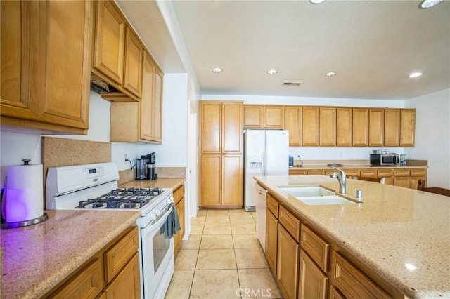 kitchen with light stone countertops, sink, white appliances, and light tile patterned floors