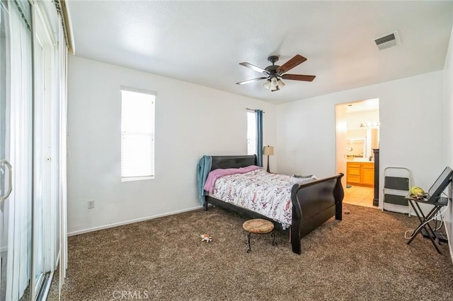 carpeted bedroom with ceiling fan, multiple windows, and ensuite bath