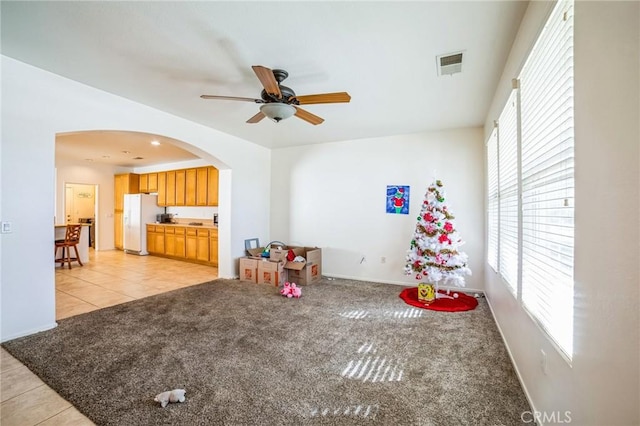 playroom featuring arched walkways, light colored carpet, a ceiling fan, baseboards, and visible vents