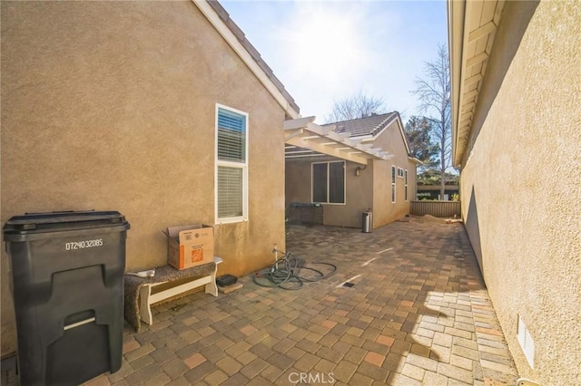 view of property exterior featuring a pergola, a patio area, fence, and stucco siding